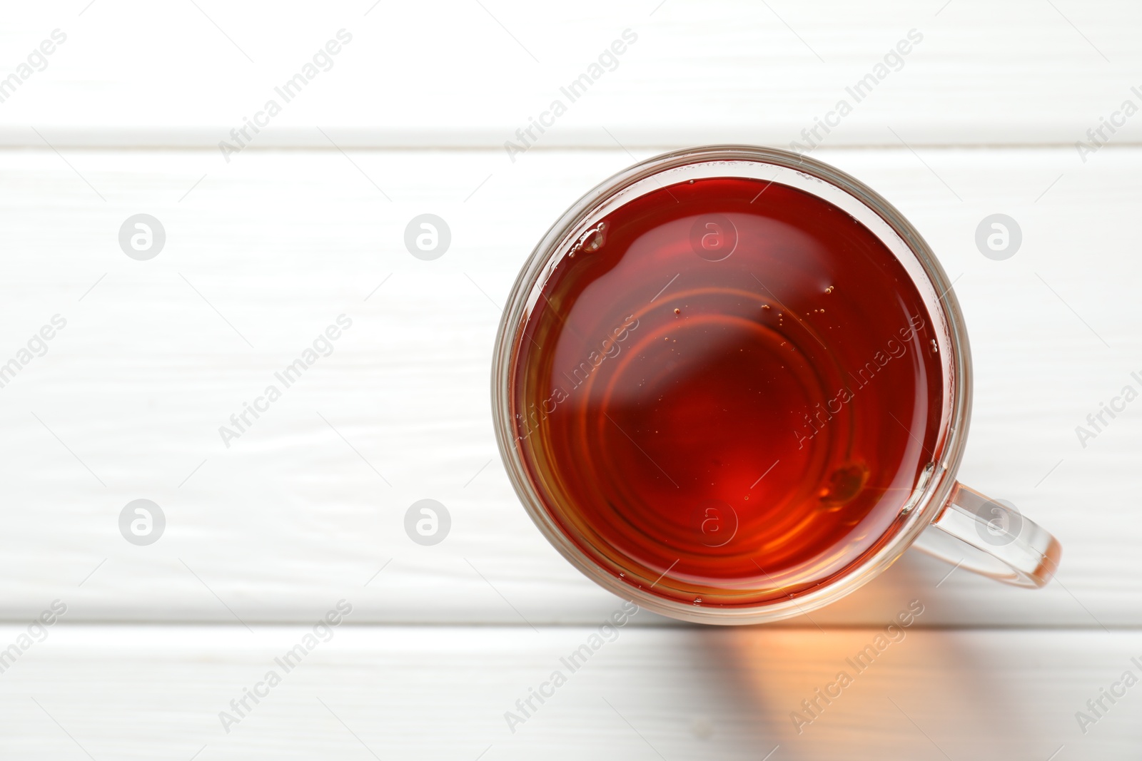 Photo of Aromatic black tea in cup on white wooden table, top view. Space for text