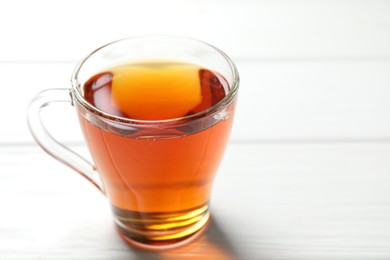 Photo of Aromatic black tea in cup on white wooden table, closeup. Space for text