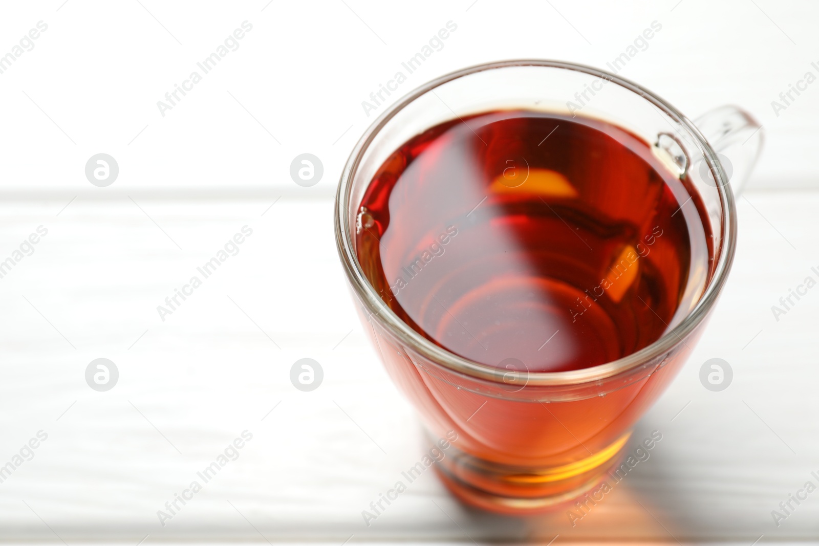 Photo of Aromatic black tea in cup on white wooden table, closeup. Space for text