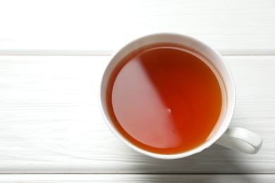 Photo of Aromatic black tea in cup on white wooden table, above view. Space for text