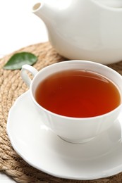 Photo of Aromatic black tea in cup and teapot on white table, closeup