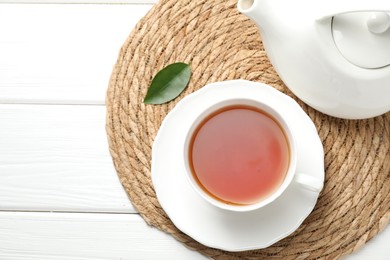 Photo of Aromatic black tea in cup and teapot on white wooden table, top view. Space for text