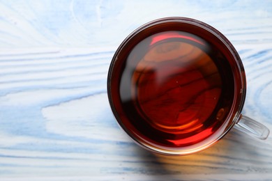 Photo of Aromatic black tea in cup on light blue wooden table, top view. Space for text