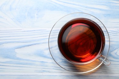 Photo of Aromatic black tea in cup on light blue wooden table, top view. Space for text