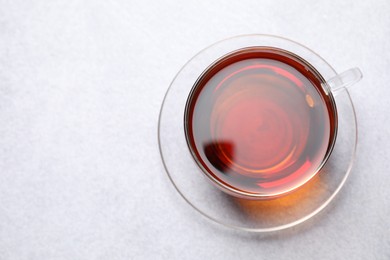 Photo of Aromatic black tea in cup on light table, top view. Space for text