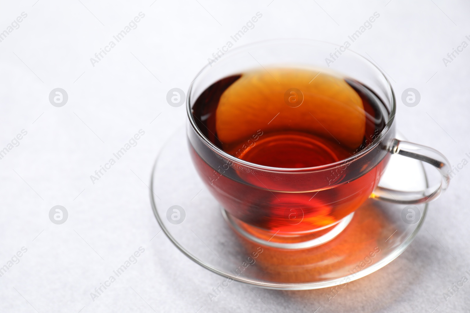 Photo of Aromatic black tea in cup on light table, closeup. Space for text