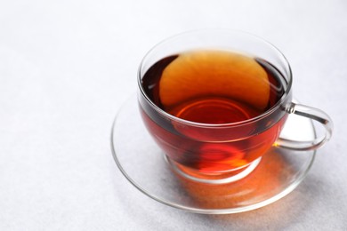 Photo of Aromatic black tea in cup on light table, closeup. Space for text