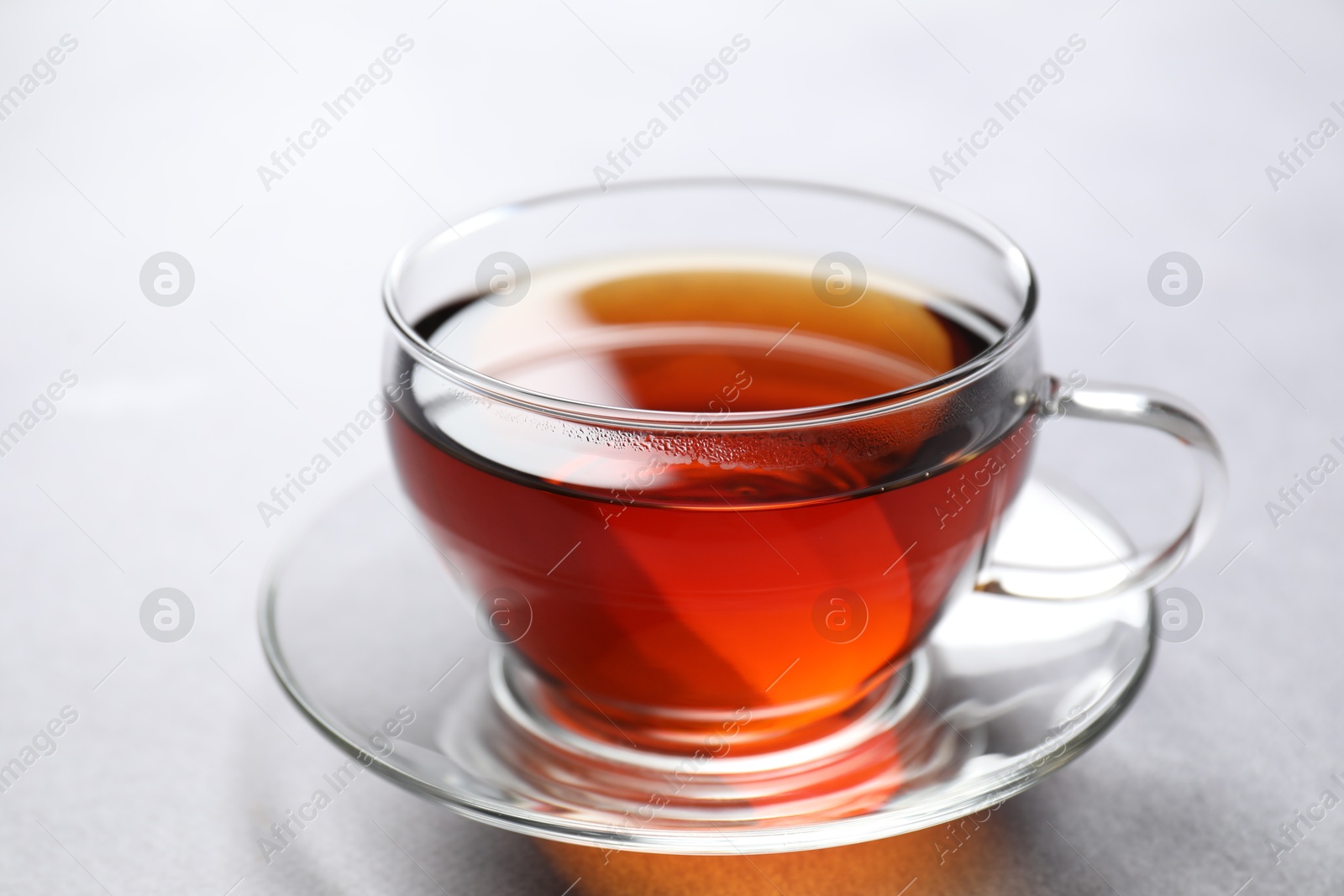 Photo of Aromatic black tea in cup on light table, closeup