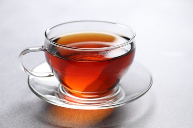 Photo of Aromatic black tea in cup on light table, closeup