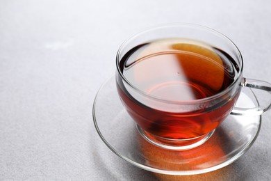 Photo of Aromatic black tea in cup on light table, closeup. Space for text