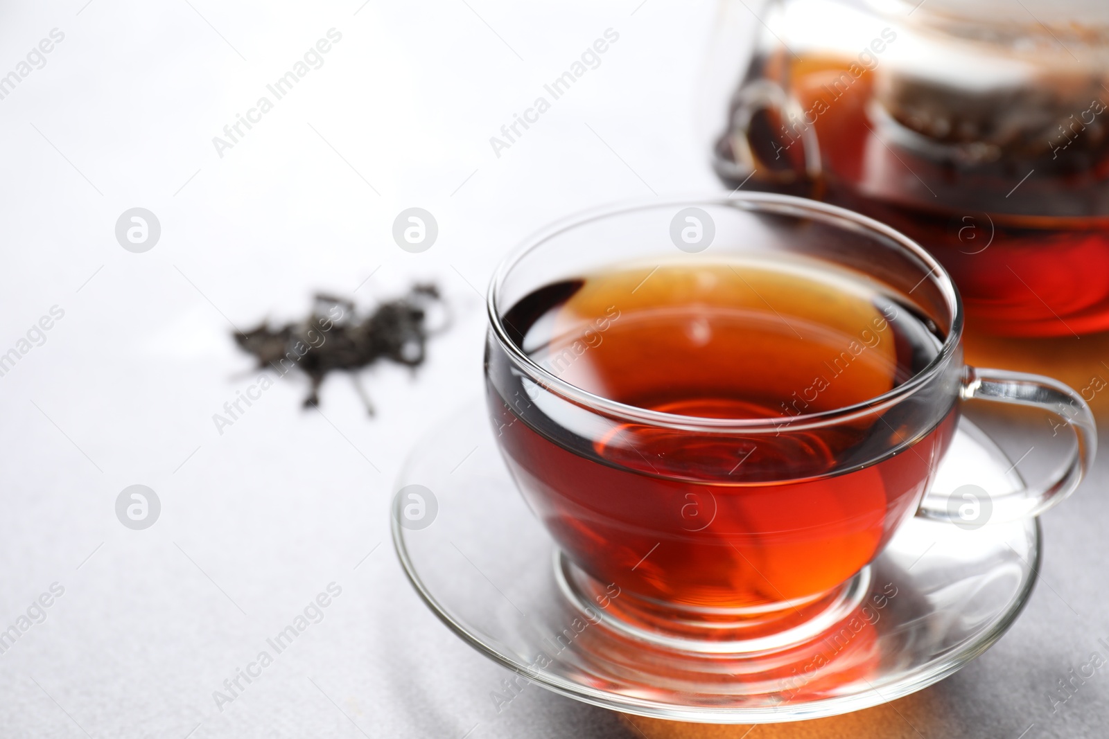 Photo of Aromatic black tea in cup on light table, closeup. Space for text