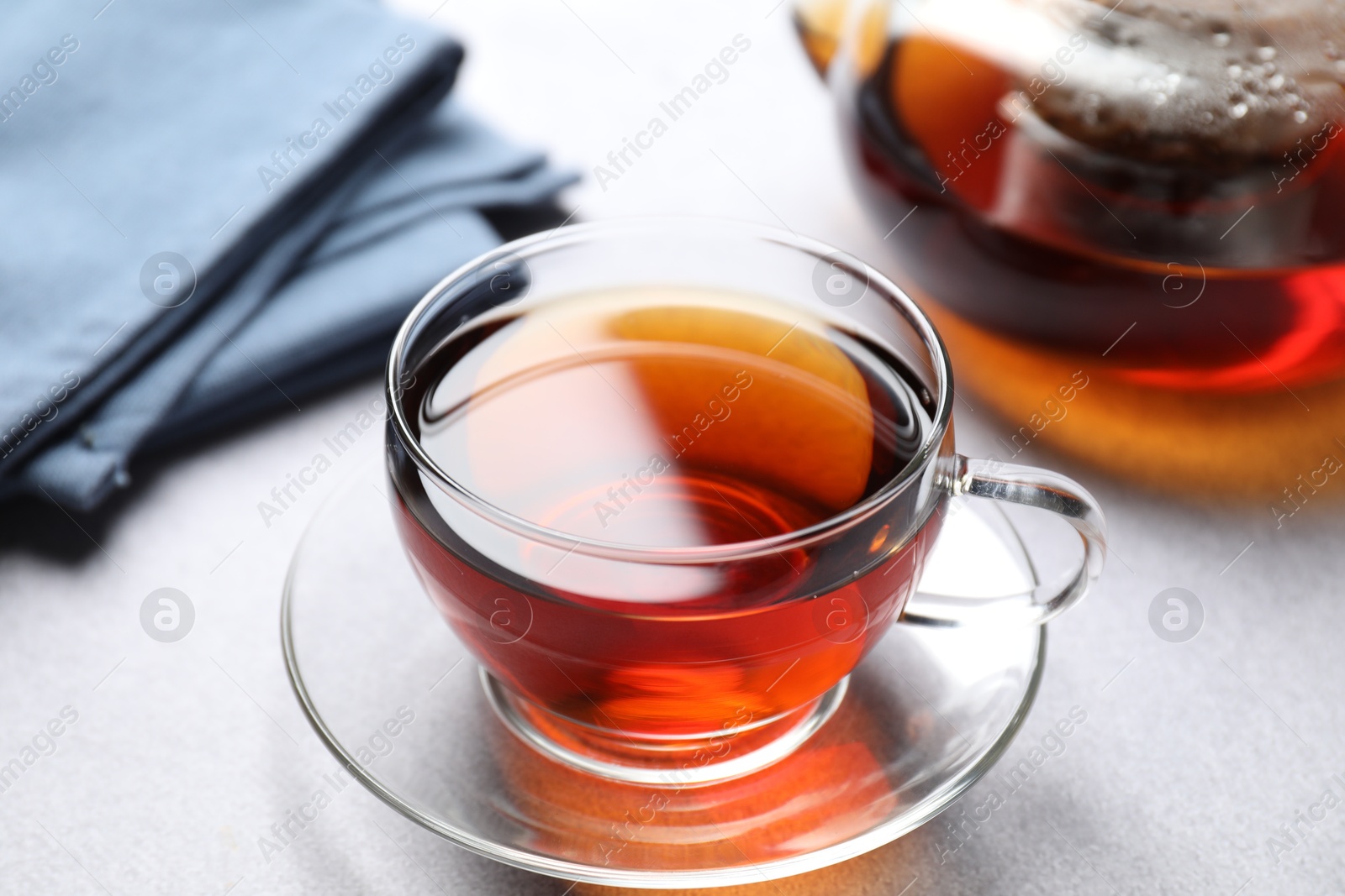 Photo of Aromatic black tea in cup and teapot on light table, closeup