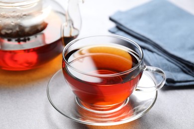 Photo of Aromatic black tea in cup and teapot on light table, closeup