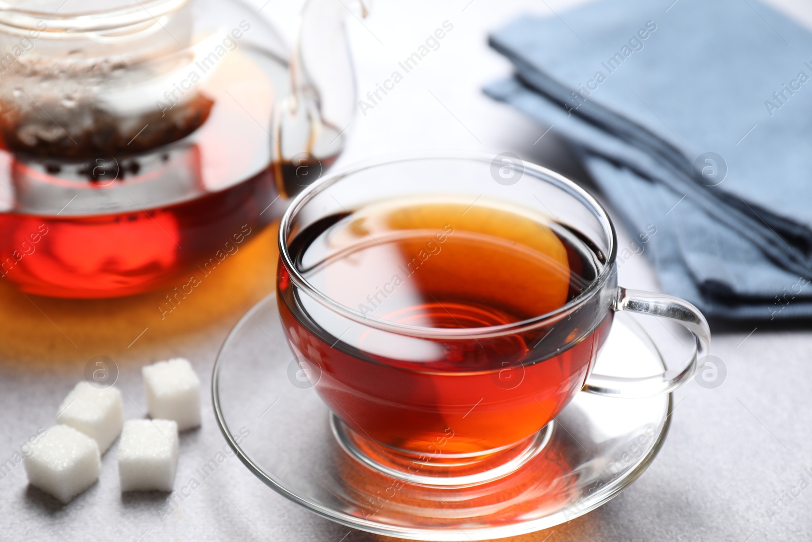 Photo of Aromatic black tea and sugar cubes on light table, closeup