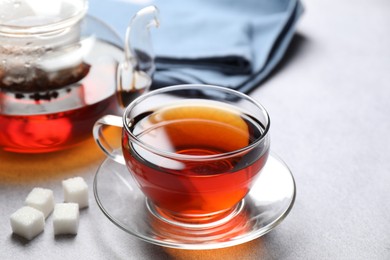 Photo of Aromatic black tea and sugar cubes on light table, closeup