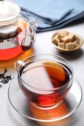 Photo of Aromatic black tea and sugar cubes on light table, closeup