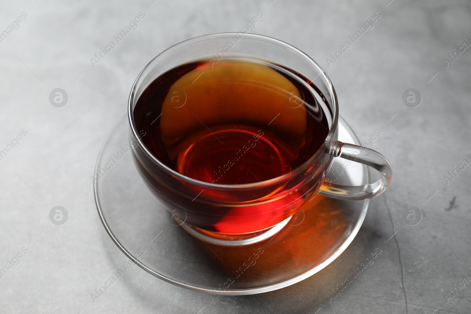 Photo of Aromatic black tea in cup on light grey table, closeup