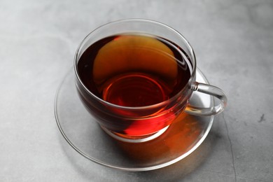 Aromatic black tea in cup on light grey table, closeup