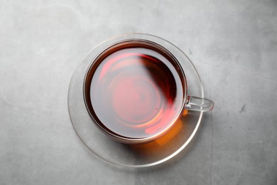 Photo of Aromatic black tea in cup on light grey table, top view