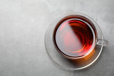 Photo of Aromatic black tea in cup on light grey table, top view. Space for text