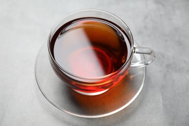 Photo of Aromatic black tea in cup on light grey table, closeup