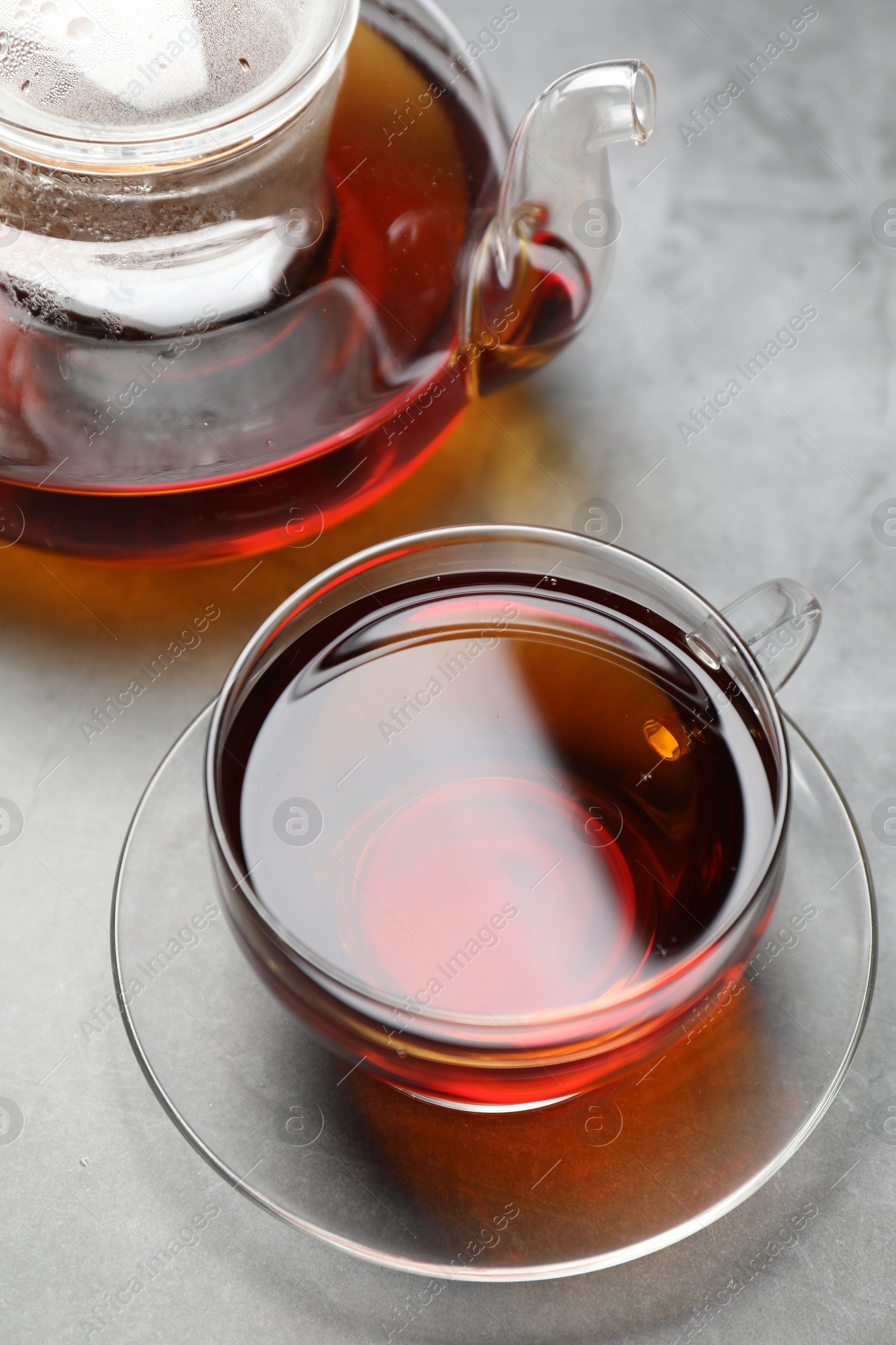 Photo of Aromatic black tea in cup and teapot on light table, closeup