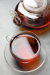 Aromatic black tea in cup and teapot on light table, closeup