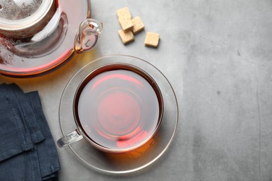 Photo of Aromatic black tea and brown sugar cubes on light grey table, above view. Space for text