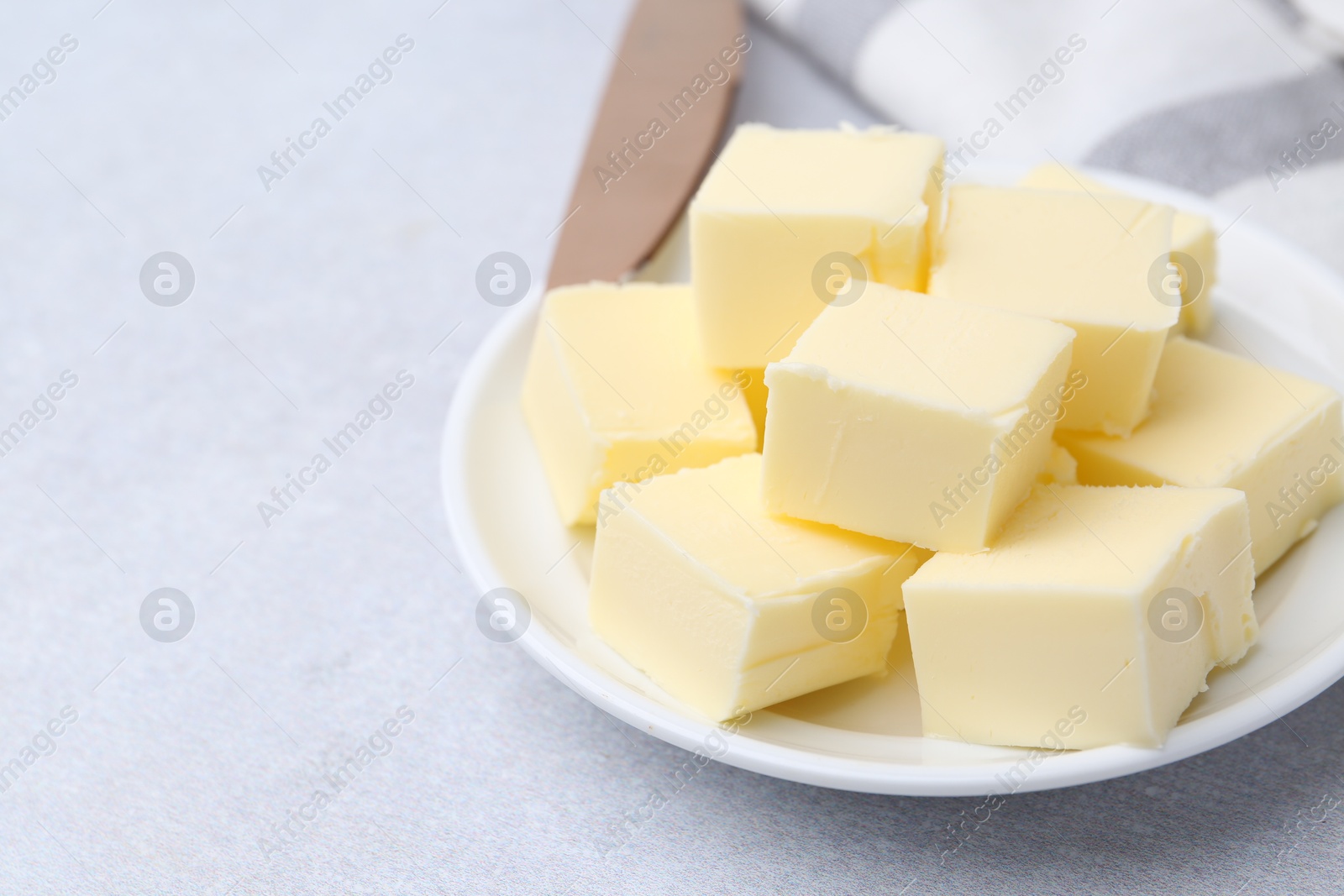 Photo of Pieces of fresh butter on white table, closeup. Space for text