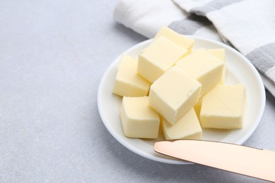 Photo of Pieces of fresh butter and knife on white table, closeup. Space for text