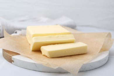 Photo of Cut block of fresh butter on white table, closeup