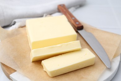 Cut block of fresh butter and knife on white table, closeup