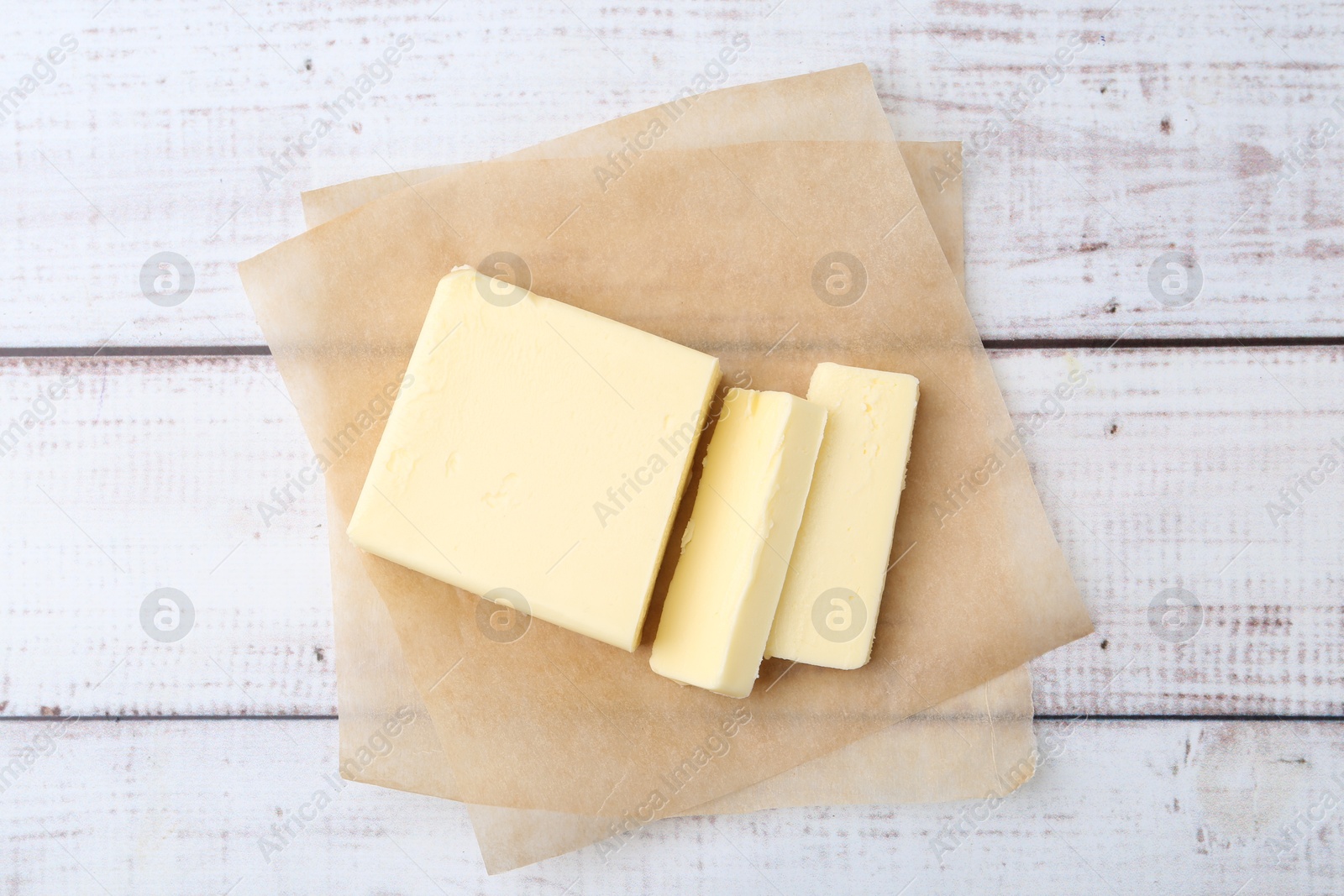 Photo of Cut block of fresh butter on white wooden table, top view