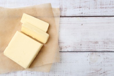 Photo of Cut block of fresh butter on white wooden table, top view. Space for text