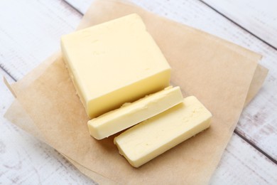 Cut block of fresh butter on white wooden table, closeup