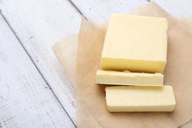 Photo of Cut block of fresh butter on white wooden table, closeup. Space for text