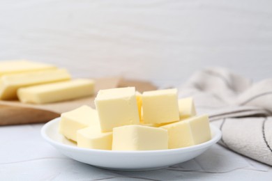 Photo of Pieces of fresh butter on white textured table, closeup