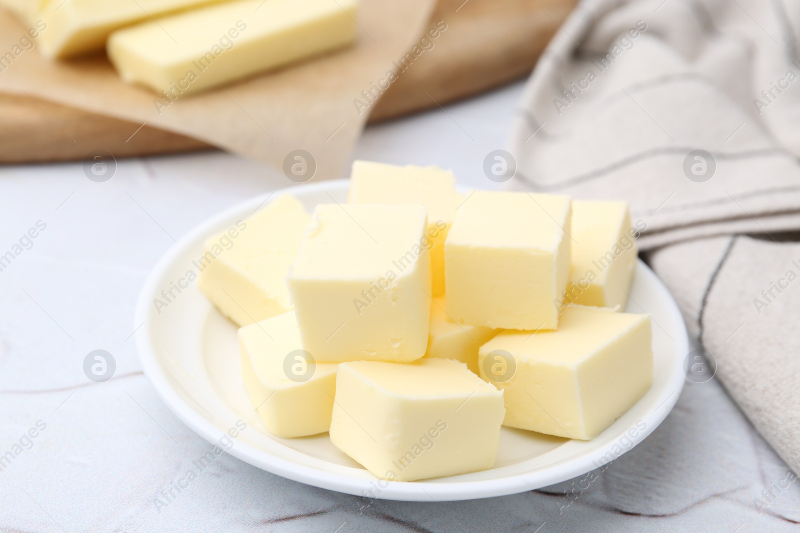 Photo of Pieces of fresh butter on white textured table, closeup