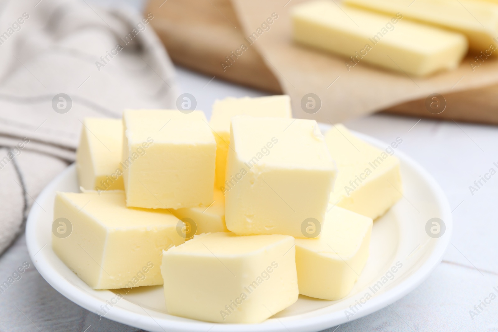 Photo of Pieces of fresh butter on white textured table, closeup