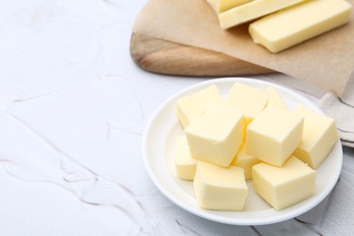 Photo of Pieces of fresh butter on white textured table, closeup. Space for text