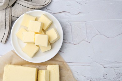 Photo of Pieces of fresh butter on white textured table, top view. Space for text