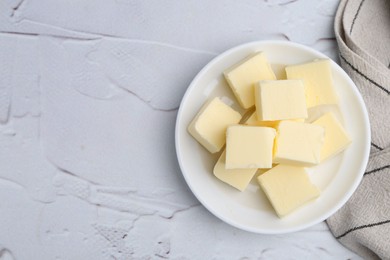 Photo of Pieces of fresh butter on white textured table, top view. Space for text