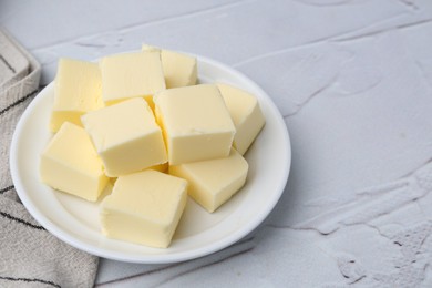 Photo of Pieces of fresh butter on white textured table, closeup. Space for text