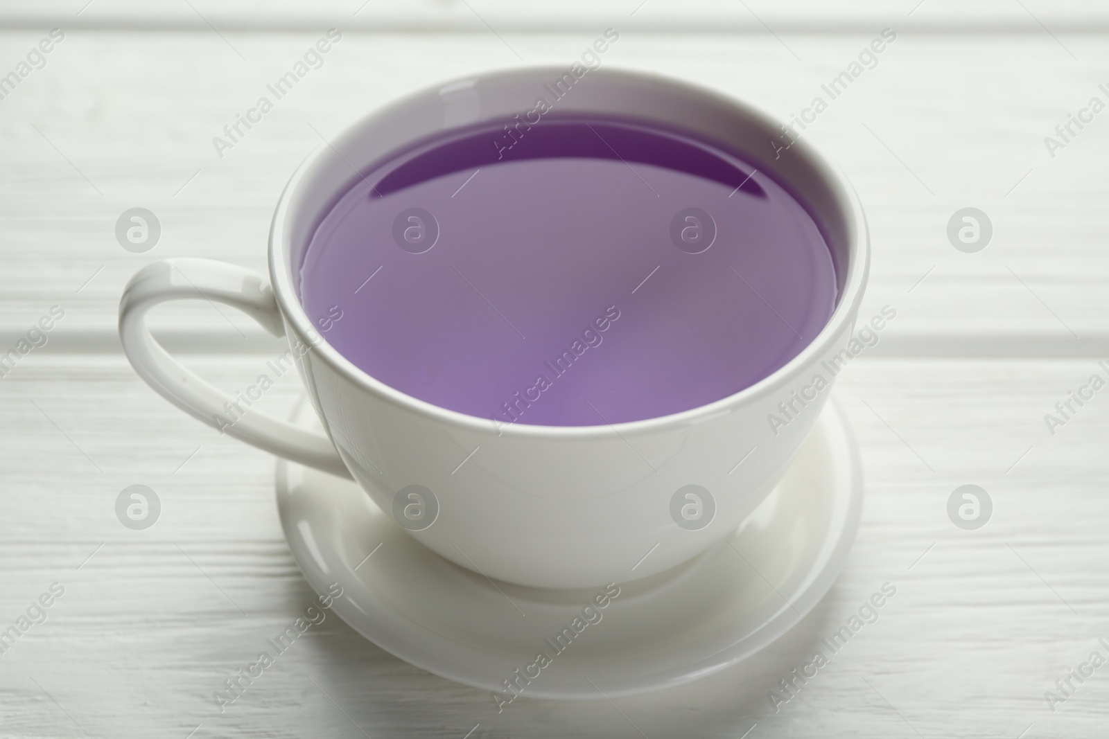 Photo of Aromatic lavender tea in cup on white wooden table, closeup