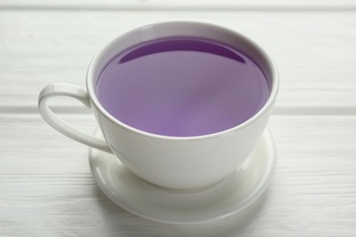 Aromatic lavender tea in cup on white wooden table, closeup