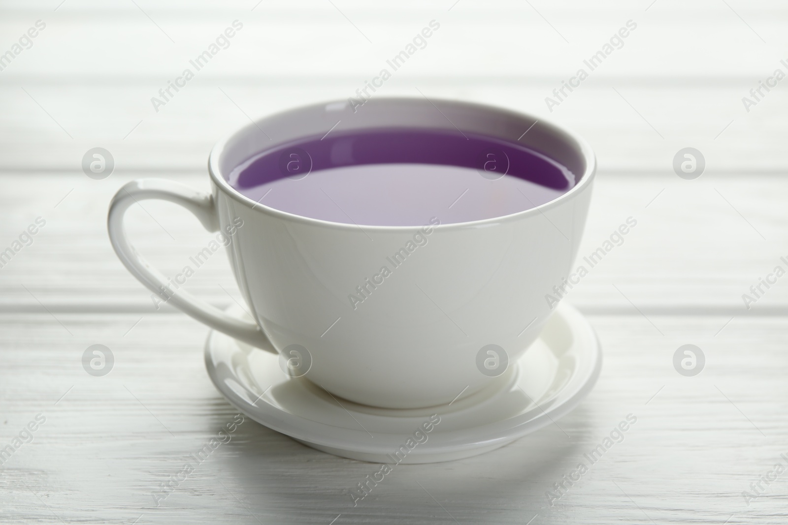 Photo of Aromatic lavender tea in cup on white wooden table, closeup