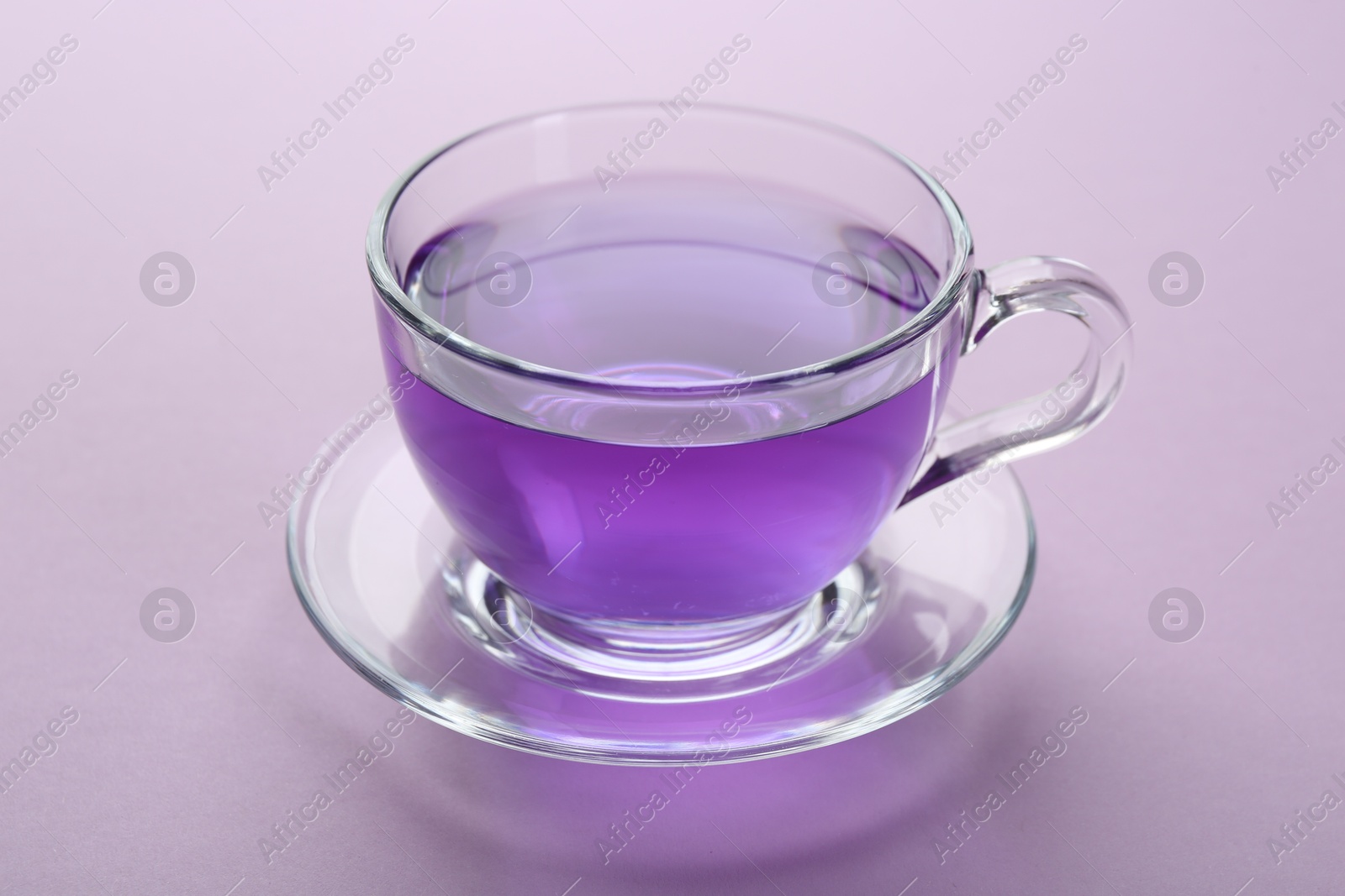 Photo of Aromatic lavender tea in cup on lilac background, closeup