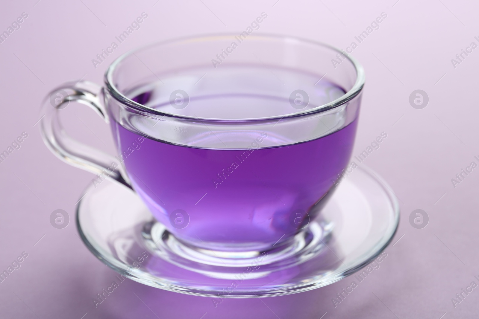 Photo of Aromatic lavender tea in cup on lilac background, closeup