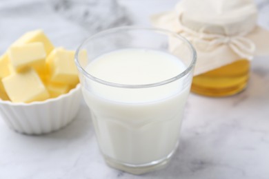 Photo of Fresh milk in glass, honey and butter on white marble table, closeup