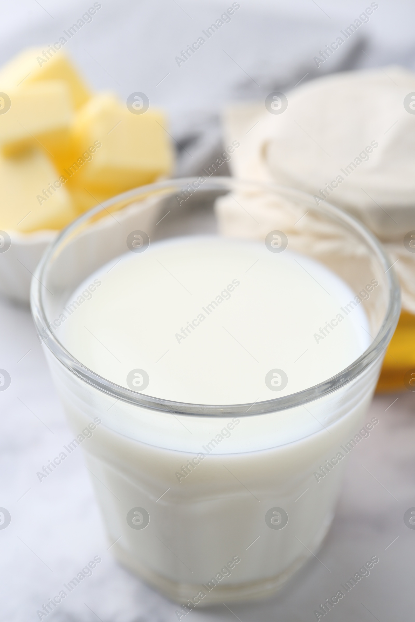 Photo of Fresh milk in glass, honey and butter on white marble table, closeup